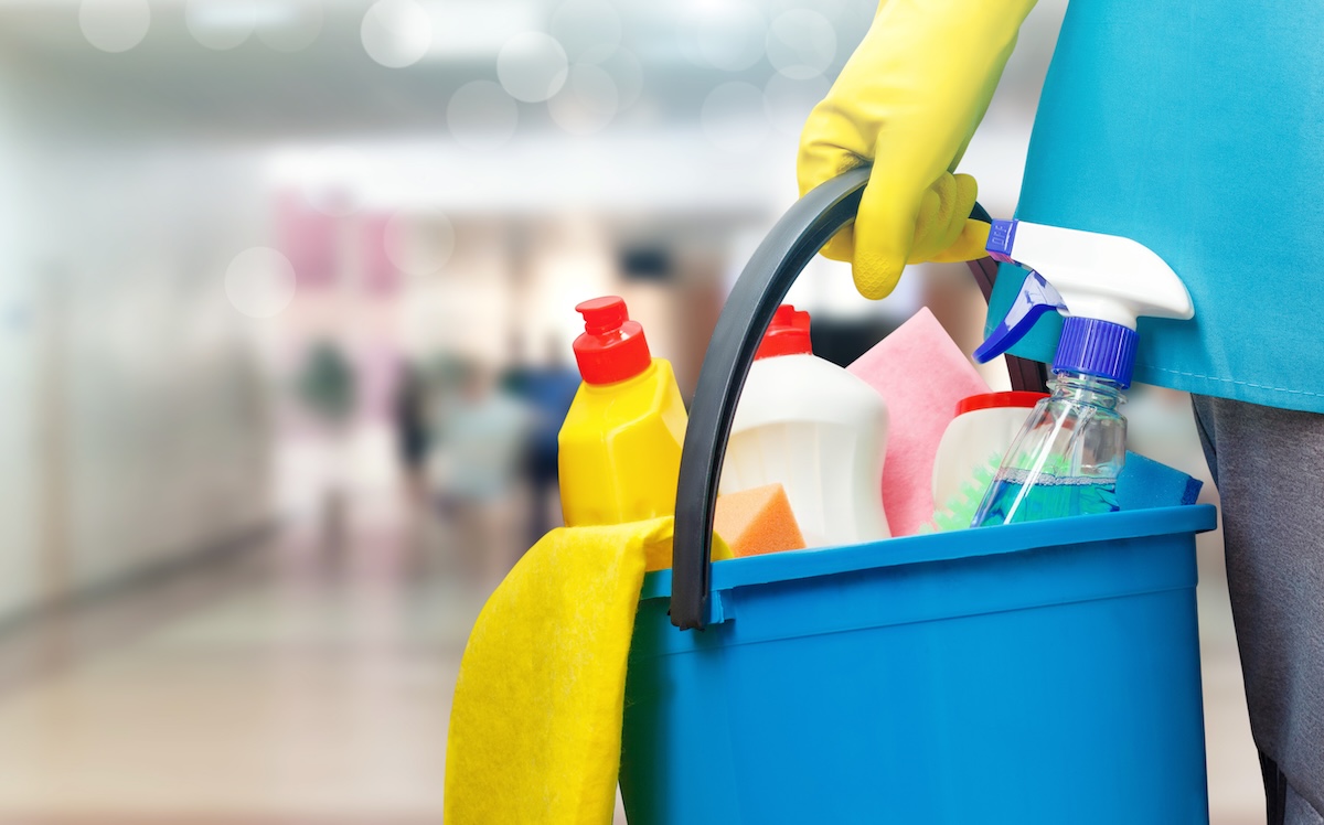 Cleaning lady with a bucket and cleaning products on blurred background.